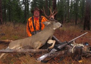 A happy hunter posing with his whitetail buck after a hunt.